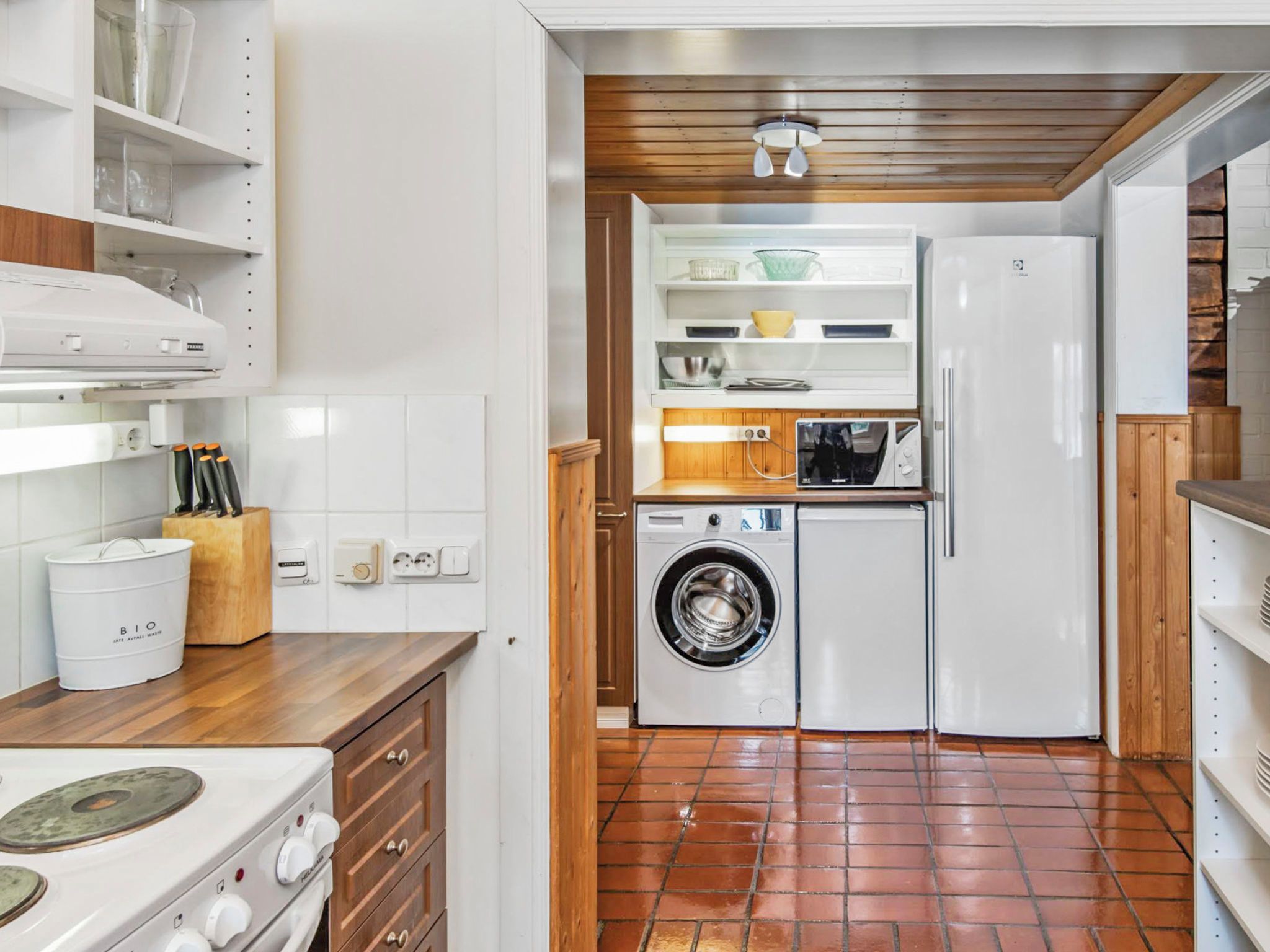 A compact kitchen with a washing machine, a microwave, and a refrigerator.