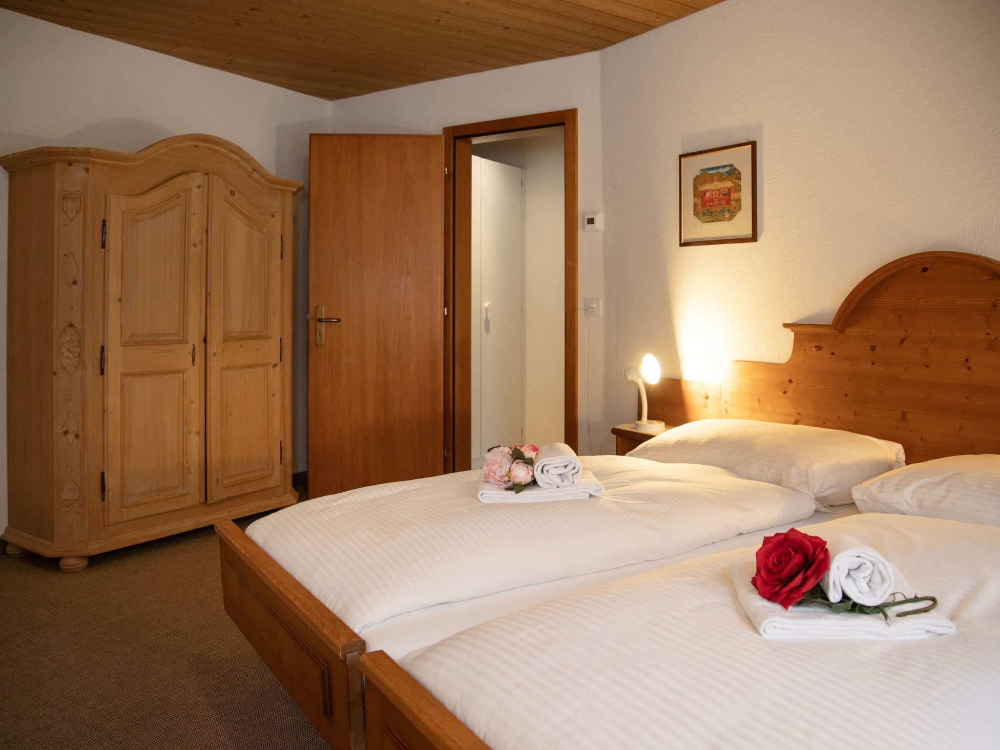 Une chambre d’hôtel avec un lit en bois, une armoire et une table de chevet avec une lampe.