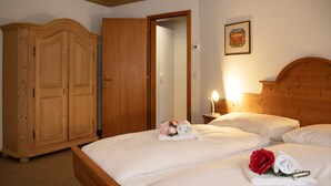 Une chambre d’hôtel avec un lit en bois, une armoire et une table de chevet avec une lampe.