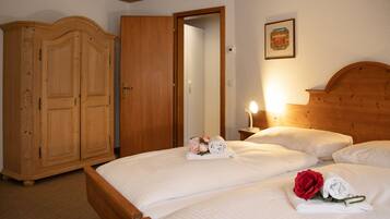Une chambre d’hôtel avec un lit en bois, une armoire et une table de chevet avec une lampe.