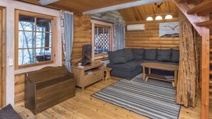 Interior acolhedor de uma cabana de madeira, com um banco, sofá e uma mesa pequena.