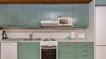 A kitchen with teal cabinets, a white microwave, a stove, and a dishwasher.