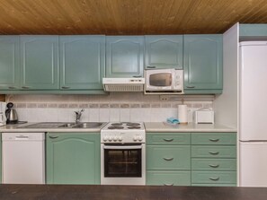 A kitchen with teal cabinets, a white microwave, a stove, and a dishwasher.