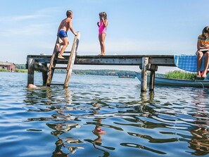 A wooden pier extending into a body of water with people on it. - Naurulokki 4 by Interhome (Parainen)