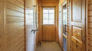 A narrow hallway with wooden walls and a tiled floor, leading to a door with a window.
