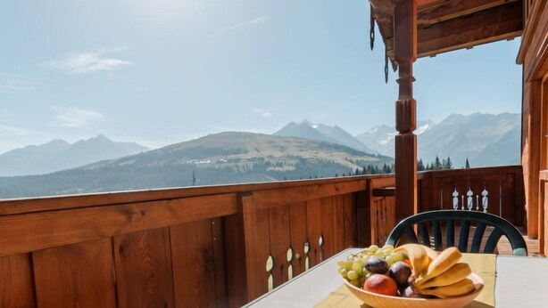 A wooden deck with a table set for a meal, overlooking a mountainous landscape. - Voithofer by Interhome (Königsleiten)