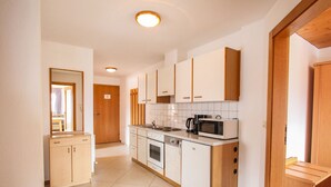 A compact kitchen with white cabinets, a microwave, a coffee maker, and a sink. - Voithofer by Interhome (Königsleiten)
