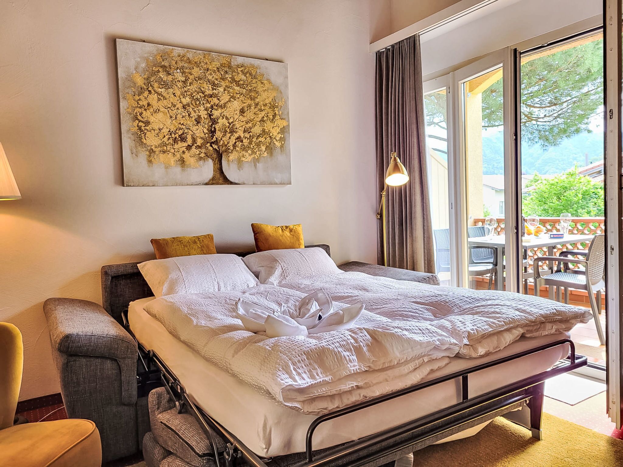 Un dormitorio con cama, una silla, una mesa y vista al exterior.