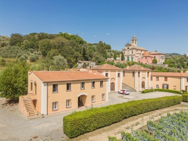 Eine Villa mit mehreren Gebäuden, einem Innenhof und Blick auf einen Hügel.