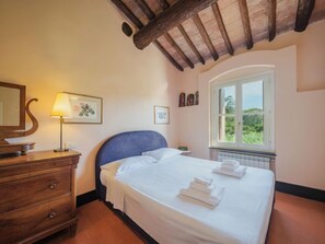 Ein Schlafzimmer mit Bett, Kommode, Fenster mit Aussicht und Lampe.