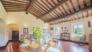 Un comedor con una mesa de madera dispuesta para una comida, un sofá y una estantería.