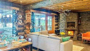 A cozy living room with a stone fireplace, a sofa, and a dining area with chairs and a table set for a meal.