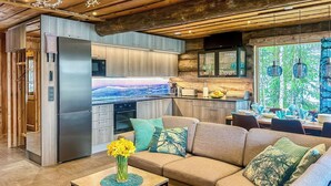 A modern kitchen with a built-in oven, a refrigerator, and a dining area with a sofa and table.