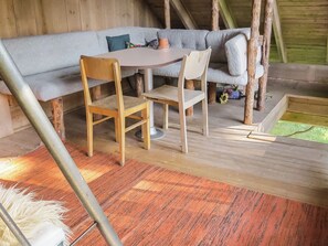 A wooden deck with a table and chairs, a sofa, and a small garden area.