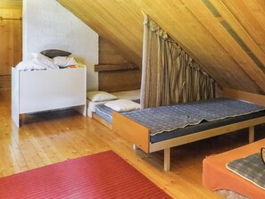 A small, attic-style bedroom with a single bed, a nightstand, and a red rug. - Passimökki by Interhome (Punkalaidun)