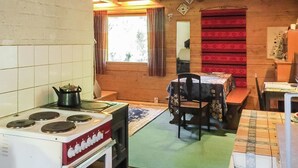A compact kitchen with a stove, a table, and chairs, and a window with curtains.
