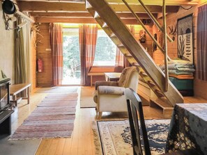 A cozy cabin interior with a wooden staircase, a sofa, a dining table, and a view of the outdoors. - Passimökki by Interhome (Punkalaidun)