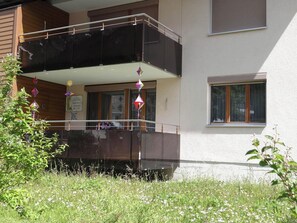A two-story building with a balcony, a window, and a sign.