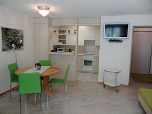 A compact living space with a dining area, kitchenette, and a TV mounted on the wall. - Blumenweg 2 Appartement/Fewo 4-Bettwohnung by Interhome (Engelberg)