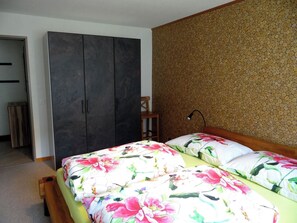 A bedroom with a bed, a wardrobe, and a wall with a textured pattern. - Blumenweg 2 Appartement/Fewo 4-Bettwohnung by Interhome (Engelberg)