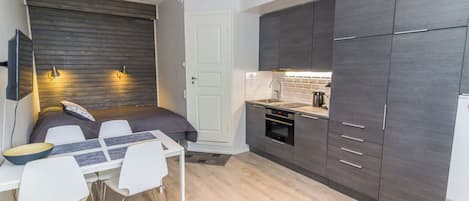 Une cuisine compacte comprenant un coin repas, un four encastré et un réfrigérateur.