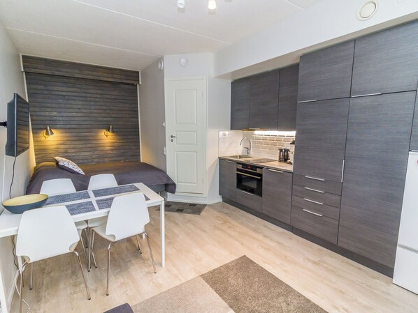 A compact kitchen with a dining area, a built-in oven, and a refrigerator.