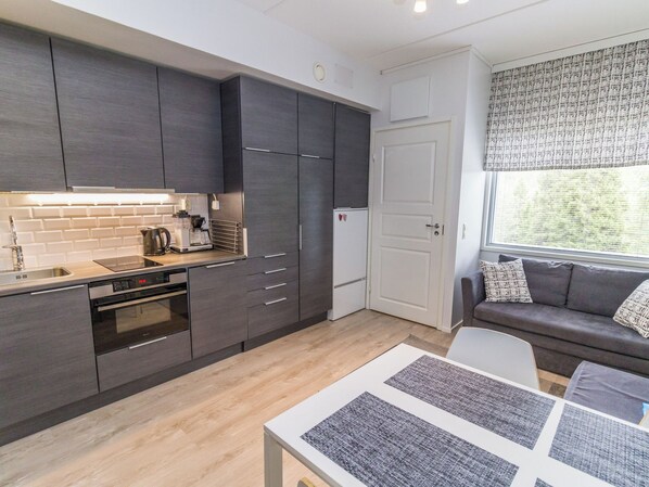 A modern kitchen with dark cabinetry, a built-in oven, and a coffee maker.