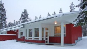 Un bâtiment enneigé, à l’extérieur rouge et aux ornements blancs, doté de grandes fenêtres et d’un porche abrité.
