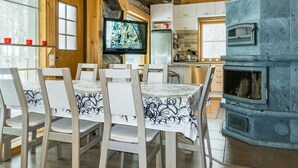 A rustic interior with a dining area, kitchen, and stone fireplace. - Kotkanpesä by Interhome (Kittilä)