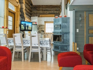A cozy living room with a fireplace, a television, and a dining area with chairs and a table.