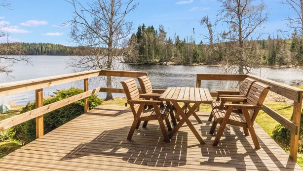 A wooden deck with a table and chairs overlooking a lake.