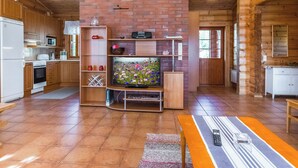 A kitchen with wooden cabinets, a brick wall, a television, and a dining area with a bench.