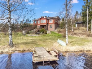 A two-story house with a dock extending into a body of water.