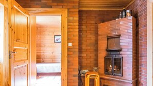 A wooden interior with a fireplace, a door leading to another room, and a small stool.