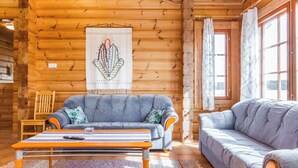 A log cabin interior with a sofa, a table, and a wall-mounted artwork.