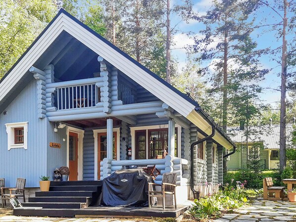 A log cabin with a porch, steps, and outdoor seating.