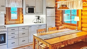 Eine gemütliche Küchenzeile im Blockhausstil mit Holzausstattung, einem Esstisch und einer Kaffeemaschine.