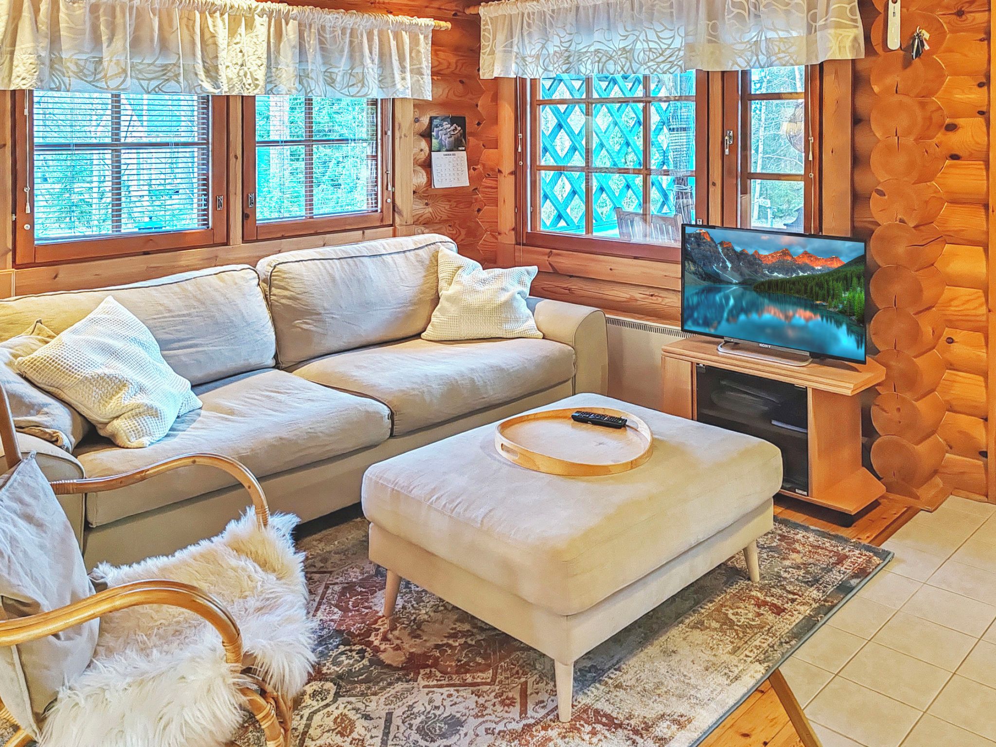 Una sala acogedora con un sofá, reposapiés y televisor sobre un panel de madera.