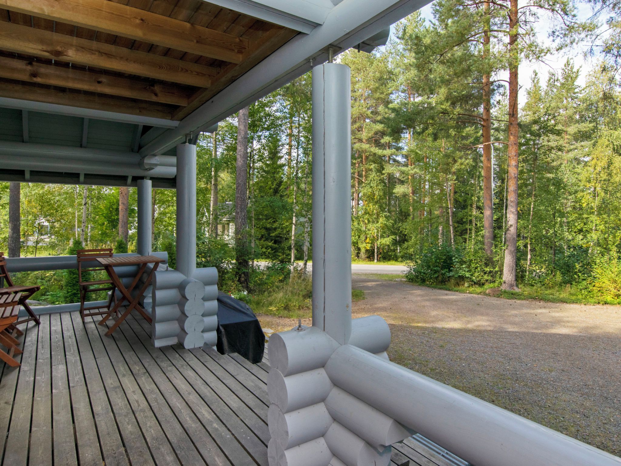 Puinen terassi, jossa on katettu alue, ulkotila istumiseen ja näkymä metsäiselle alueelle.