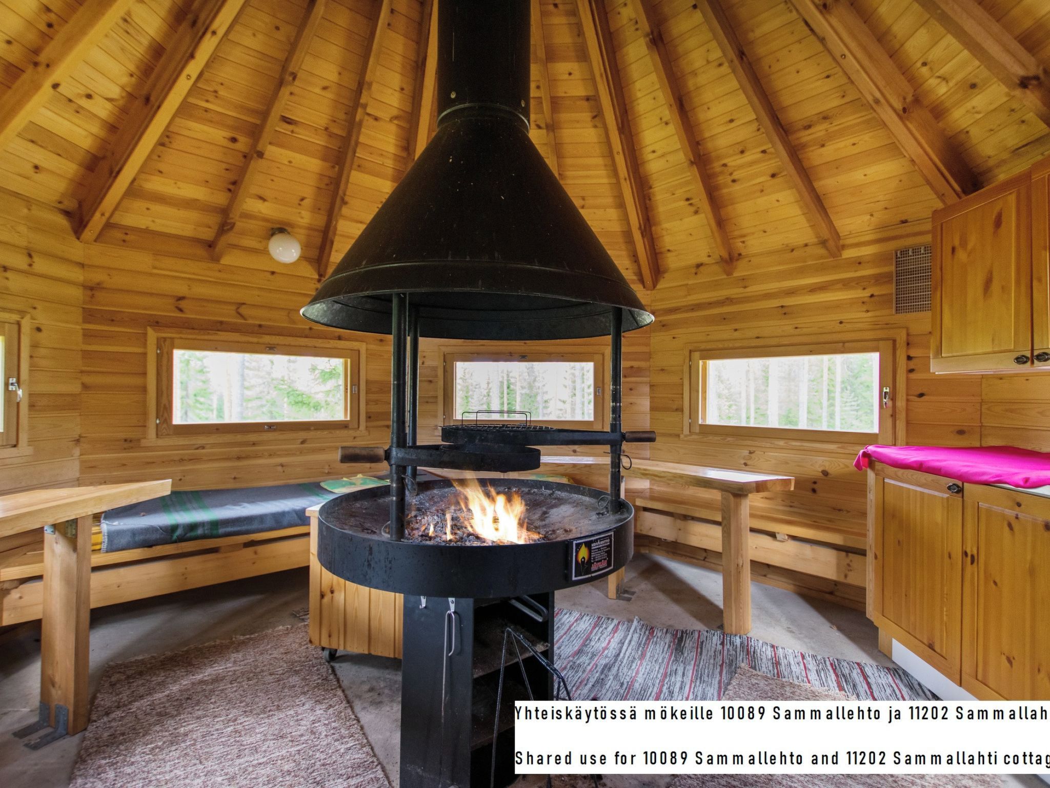 Een chaletinterieur met een houten kachel, houten banken en een hoge nok.