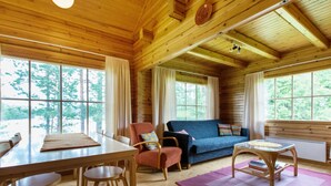 Een gezellig cabin interieur met een houten eettafel, stoelen, een bank en een kleine tafel met een kleed.