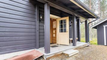 A wooden house with a porch, a door, and a small window.