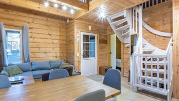 Ein Holzblockhaus-Interieur mit Essbereich, einer Couch und einer Wendeltreppe.