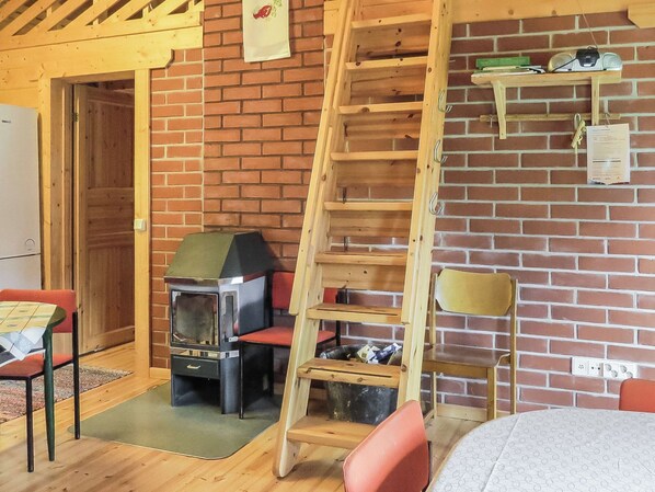 A cozy room with a brick wall, a wooden ladder, a small table, and a chair. - Vacation home Muisku by Interhome (Punkalaidun)