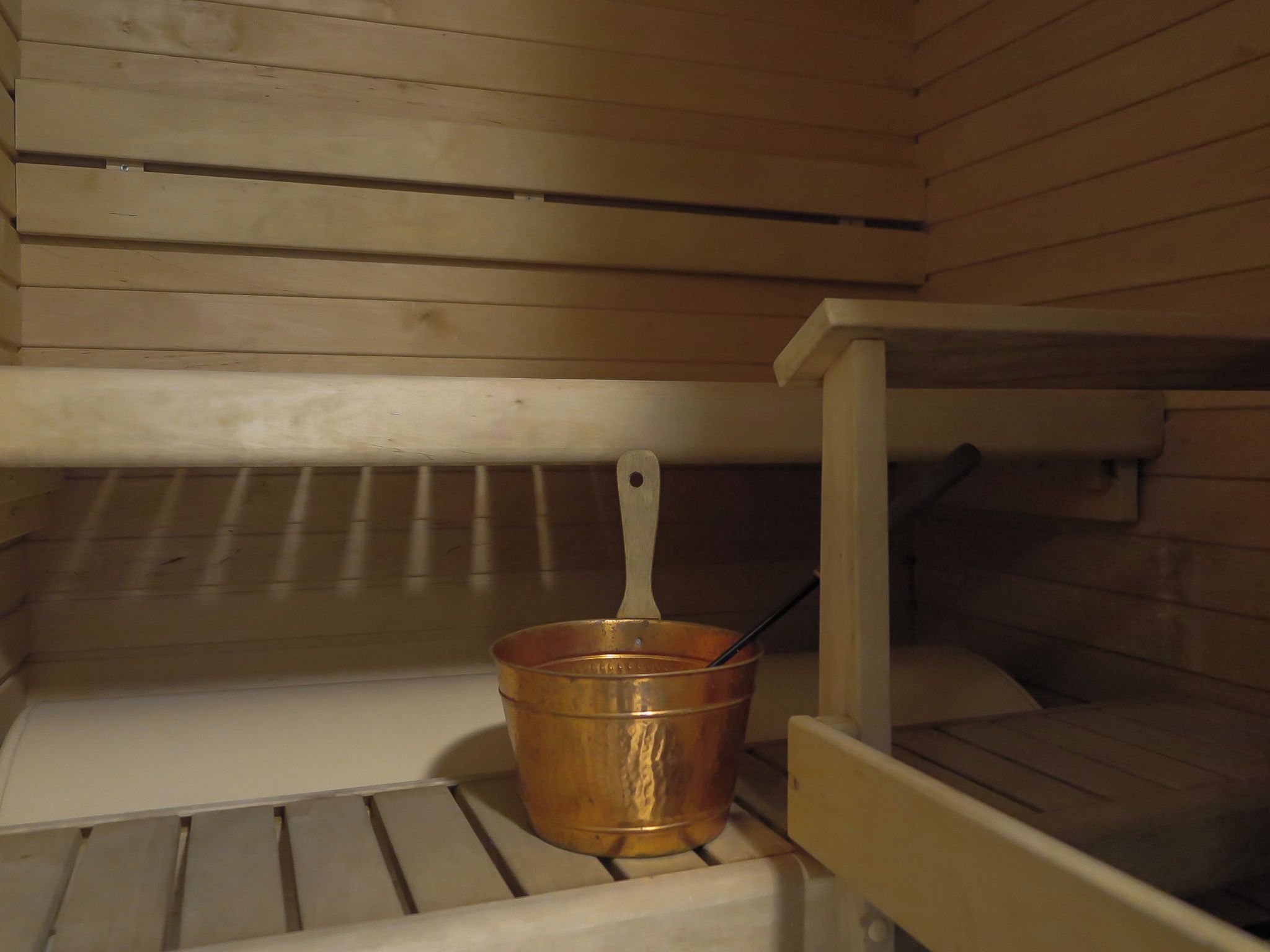 Een metalen emmer met handvat op een houten plank.