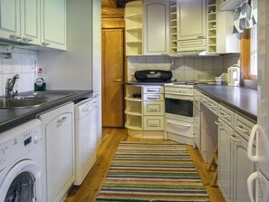 Una cucina compatta con elettrodomestici bianchi, una lavatrice e un tappeto a righe.