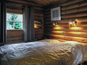 Una camera da letto in legno con un letto, una finestra e un punto luce a parete.