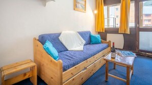 Een knus interieur met een houten bed, een tafeltje met glazen en een raam met gordijnen.