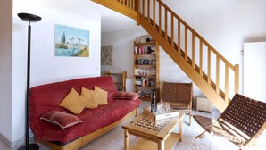 Una sala de estar con un sofá rojo, una mesa de centro de madera, una estantería y una escalera de madera.