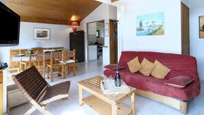 Una sala de estar acogedora con un sofá rojo, muebles de madera y una mesa de comedor.